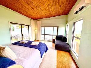 a bedroom with a bed and a couch and windows at Driftwood in Bargara +20 photos