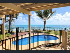 a fence with a swimming pool in front of the ocean at Driftwood in Bargara