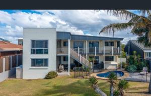 a large white house with a yard with a pool at Driftwood in Bargara