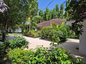 een tuin met planten en een huis op de achtergrond bij KIVi Cottages Nungwi in Nungwi