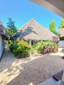 een huis met een rieten dak en een aantal struiken bij KIVi Cottages Nungwi in Nungwi