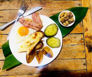 a white plate of food with eggs and vegetables on a table at The Sanctuary Homestay in Phumĭ Don Téav +18 photos