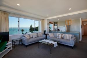 ein Wohnzimmer mit zwei Sofas und einem großen Fenster in der Unterkunft Beaumont Apartments in Mount Maunganui