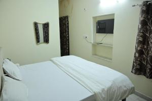 a white bed in a room with a tv at The Mapple Stay in Jodhpur