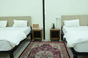 two beds in a room with a rug on the floor at The Mapple Stay in Jodhpur