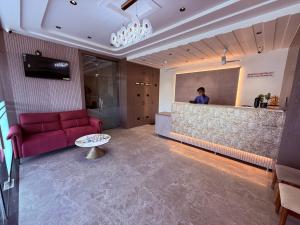 Ein Wohnzimmer mit einem roten Sofa und einer Person hinter einem Tresen in der Unterkunft Hotel Kushala Grand, Dombivali in Mangrul