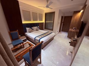 ein Schlafzimmer mit einem Bett, einem Schreibtisch und einem Stuhl in der Unterkunft Hotel Kushala Grand, Dombivali in Mangrul