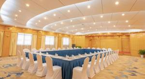 una grande stanza con un lungo tavolo e sedie bianche di Excemon Beach Hotel Beihai a Beihai Altre 223 foto