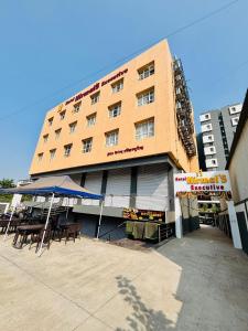 a building with tables and umbrellas in front of it at Hotel Nirmal's Executive in Pune