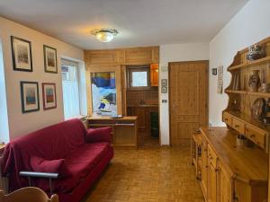 a living room with a red couch and a kitchen at Casa di Lilly in Moena