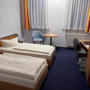 a hotel room with two beds and a table and chairs at Turmhotel Schwedt in Schwedt +49 photos