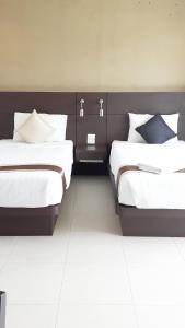 two beds in a hotel room with white sheets at Putterhouse in Rawai Beach