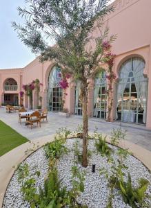 a tree in front of a pink building at Sukoon Gah in Bedla
