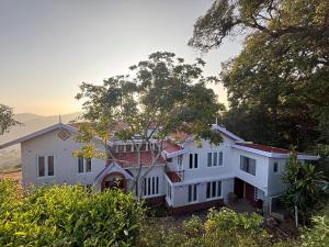 a large white house with trees in the background at Burnside Cottage in Kotagiri