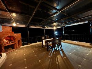 a stage with a table and chairs and a brick fireplace at Burnside Cottage in Kotagiri