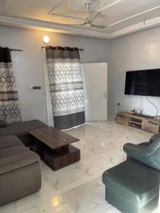 a living room with a couch and a table and a tv at Immeuble do-rego in Lomé