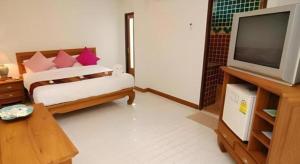 un soggiorno con un letto e una televisione di Fah Place Hotel a Nan