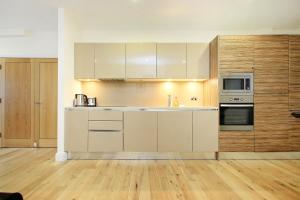 a kitchen with white appliances and wooden floors at Apartments at Camden Square in London