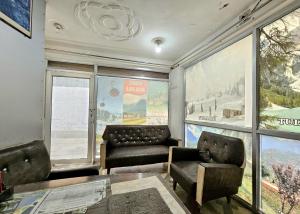 a living room with a couch and chairs and windows at Kashmir naaz in Srinagar