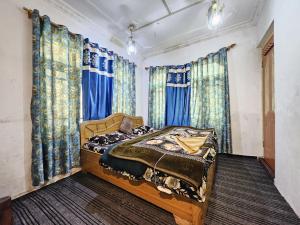 a bedroom with a bed with blue curtains at Kashmir naaz in Srinagar