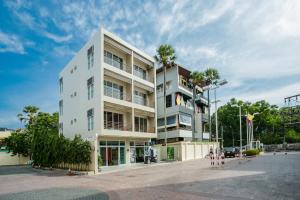 a white building with palm trees in front of it at Casa De Coral Boutique Hotel in Kata Beach