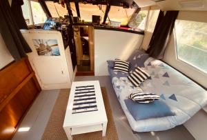 a room with a couch and a table in a room at Bateau Péniche à quai 6 couchages in Colombiers +20 photos