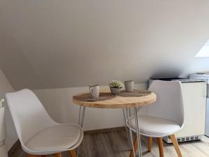 a small table with white chairs and a kitchen at Apartments Brunsbüttel in Brunsbüttel +3 photos
