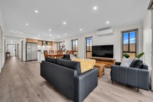 a living room with two black couches and a television at IK homes in Clyde North