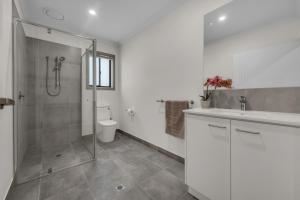 a bathroom with a shower and a sink and a toilet at IK homes in Clyde North +14 photos