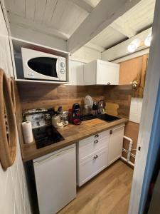eine kleine Küche mit weißen Schränken und einer Mikrowelle in der Unterkunft Petit cocoon in Les Angles