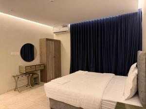 een slaapkamer met een bed en een blauw gordijn bij ركن صحاري للشقق المخدومة ضبا Rukn Sahari for Served Apartments in Ḑubā +142 foto's