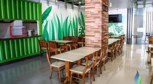 een restaurant met tafels en stoelen en een groene muur bij Sunrise Hotel in Malang