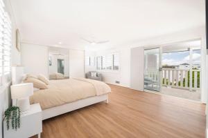 a white bedroom with a large bed and a balcony at Dalton Escape in Nelson Bay