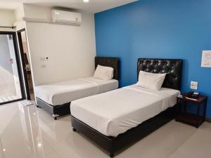 two beds in a room with a blue wall at เคทูกรีน สุพรรณบุรี in Ban Hua Phrong