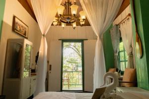 a bedroom with a bed with a window and a chandelier at The Antique Riverside Resort in Ban Pong
