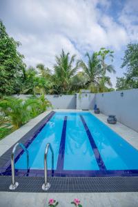 a large blue swimming pool with trees in the background at Gone4Coastal - Cabana in Hikkaduwa