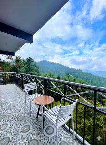 two chairs and a table on a balcony with a view at Baldeyan Breeze - 2BHK Apartments - Private Balcony in Shimla