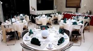 een kamer met witte tafels en stoelen met groene servetten bij Nikita Palace in Bukittinggi