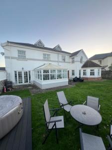 a large white house with a table and chairs at Family & friends get together birthday hot tub in Porthcawl
