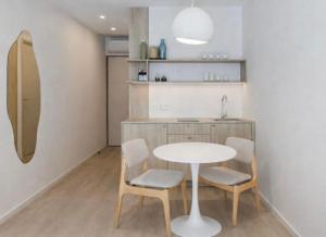 een keuken met een tafel, 2 stoelen en een wastafel bij Wave 21 Nida Self Check-In Apartment in Nida