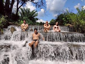 four people in bathing suits sitting on a waterfall at Doi Lom Elephant farmstay in Ban Muang Kut +3 photos
