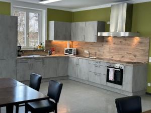 een keuken met grijze kasten en een tafel met stoelen bij Gästehaus Sandra in Sulzbach-Rosenberg