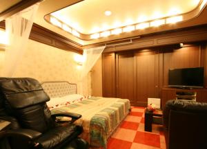- une chambre avec un lit, une chaise et une télévision dans l'établissement オーラリゾート四條畷, à Shijonawate