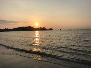 a sunset on the beach with the sun setting at MP Resort Koh Phayam in Ko Phayam