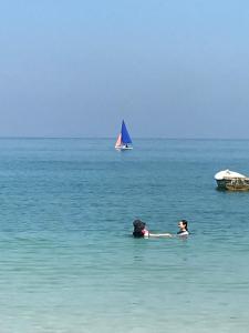 two people swimming in the ocean with a sail boat at MP Resort Koh Phayam in Ko Phayam