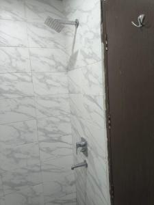 a shower with white marble walls and a door at Chandigarh city centre in Zirakpur
