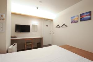 a bedroom with a desk and a tv on the wall at E10 Hostel in Tokyo