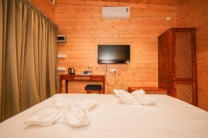 a bedroom with a white bed with a tv on the wall at Oyster Bay Beach Resort in Anjuna +72 photos