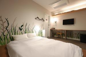 a bedroom with a white bed and a wall with plants at E10 Hostel in Tokyo +7 photos