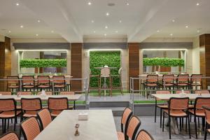 a restaurant with tables and chairs and a green hedge at Hotel Karl Residency in Mumbai